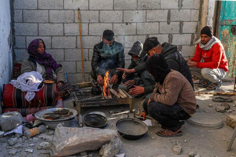 在加沙南部的拉法,当地人民在被炸毁的屋外准备食物。(法新社)