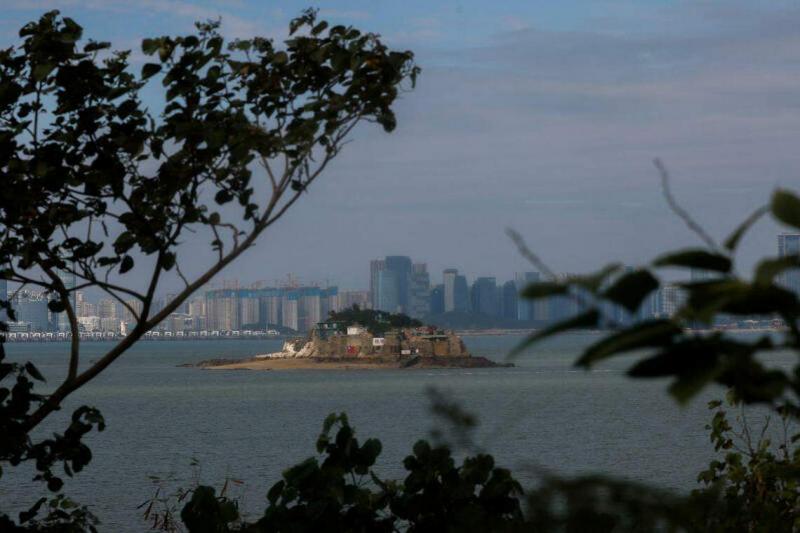 金门离岛小岛狮屿,该岛插有中华民国国旗,对面高楼大厦是厦门的城市天际线。(路透社)