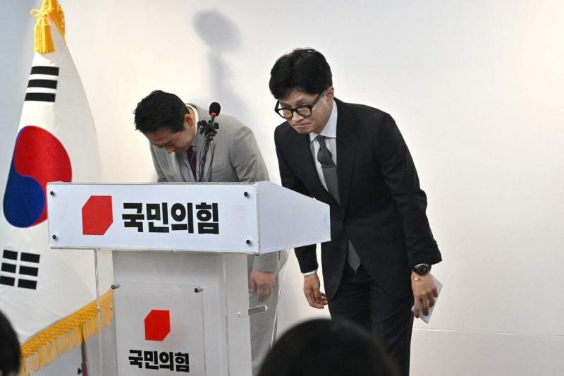 韩国国民力量党党首韩东勋(右)星期四在首尔党总部举行的新闻发布会上鞠躬,为他领导的执政党在国会选举中惨败引咎辞职。(法新社)