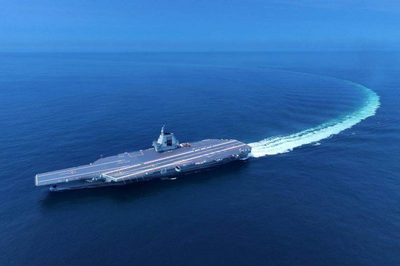 福建舰在蓝色海面上清晰地划出一道航迹,白色浪花形成一定弧度。(新华社)