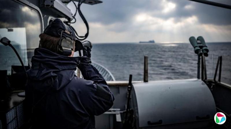 Carlskrona号巡逻舰的一名船员正用望远镜观察地平线上的一艘货船。