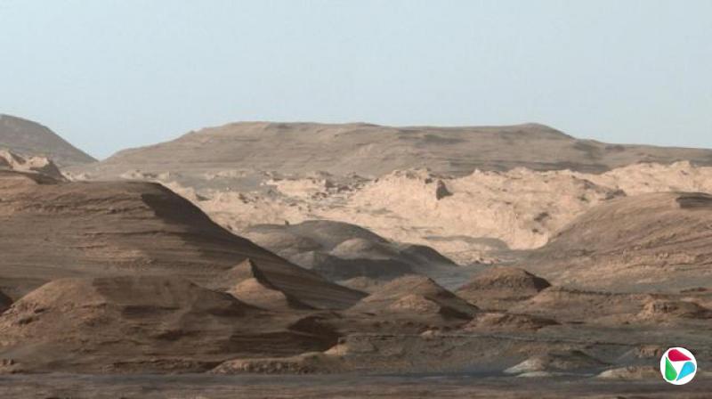 ��Ƭ��ʾ��������ɽ�ϸߵ�����ǰ���пɼ�����ɫ�ĵش�������һЩС���꣬�����һ���¶��Դ��б�¡���Ƭ�����ǽ�ǳɫ����������Ϊ��᫵���ʯ����Զ����ɼ�������״��Բ���¶Ƚϻ���ɽ�����Ϸ��ɼ�����ճ����ɫ��