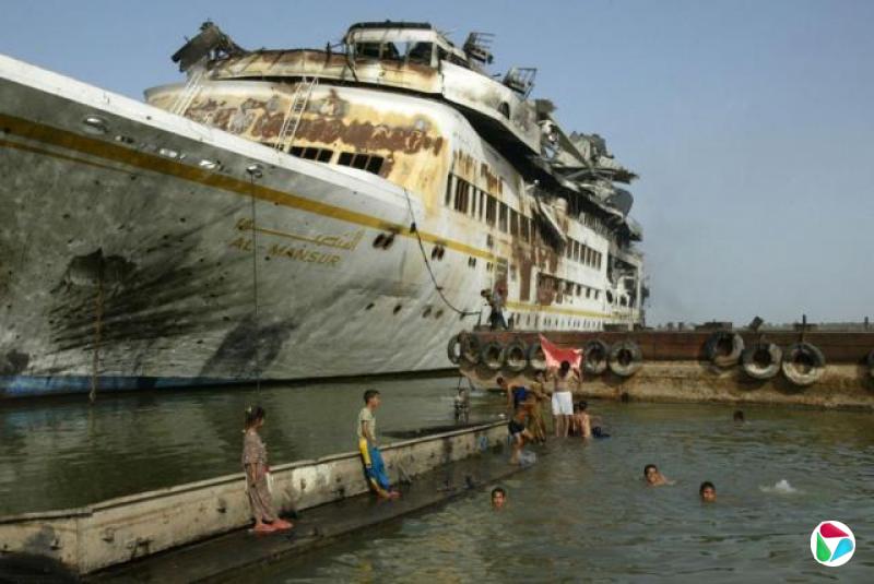 �������ڸۿ���Ӿ����Щ������վ��һ���⼣�߰ߵĴ��Ե�ƽ̨�ϣ���ͷ�ý�ɫ��ĸд�š����ն�����Al Mansur������̥�����ڸۿڱ�Ե��