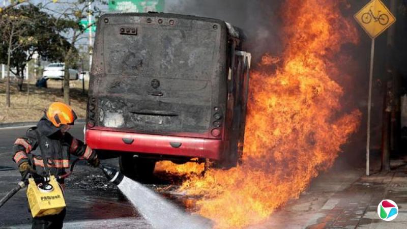 一名消防员正向一辆在墨西哥因贩毒集团暴力而被纵火的燃烧巴士喷射水柱