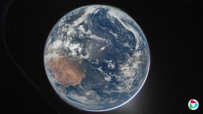 一张从太空拍摄的地球照片,画面中央是映衬在漆黑太空背景中的地球。它呈现圆形、湛蓝的外观,可见云层分布,顶端还能看到一抹淡绿色的极光。